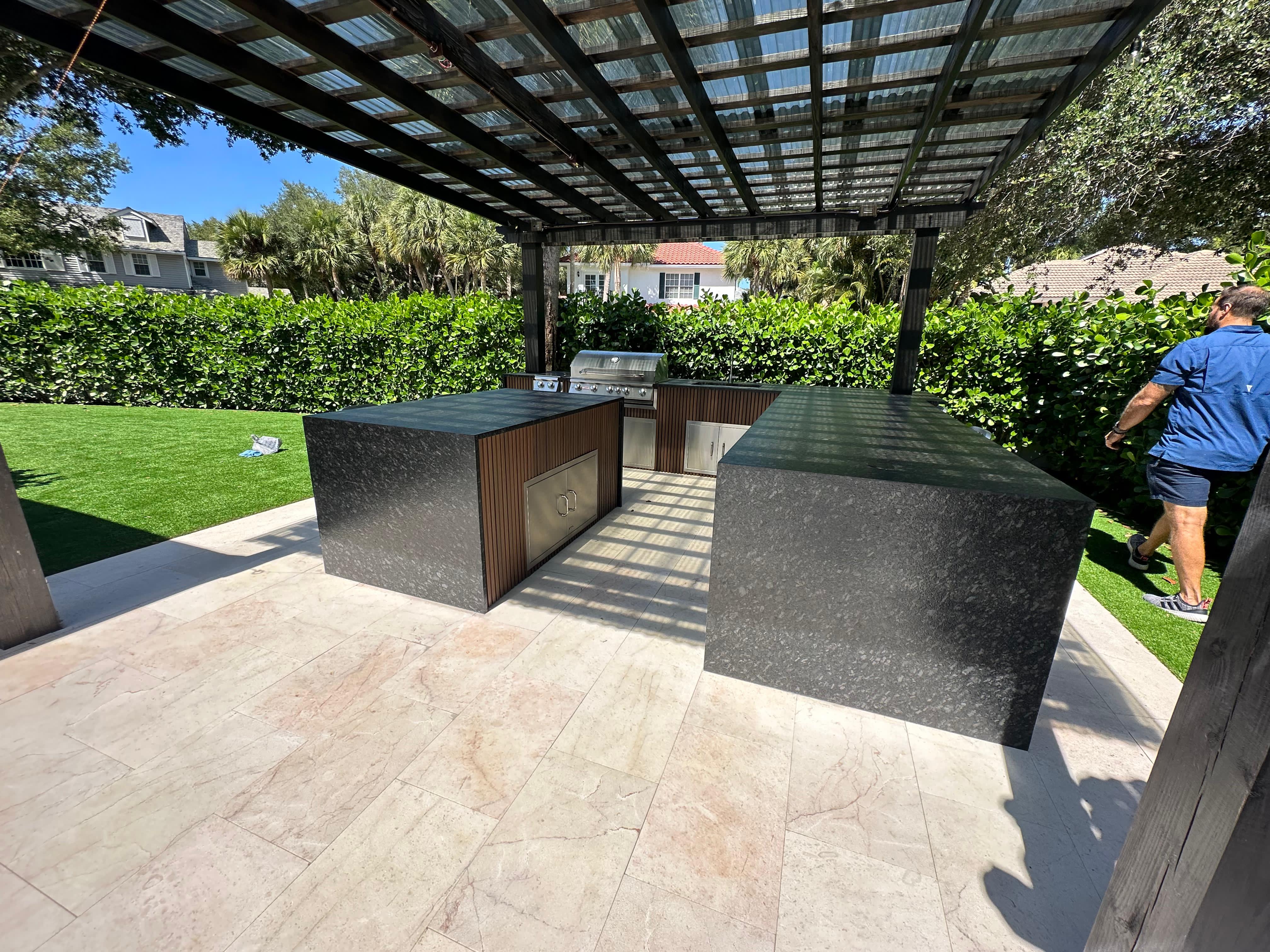 Modern outdoor kitchen with built-in grill and bar setup under pergola