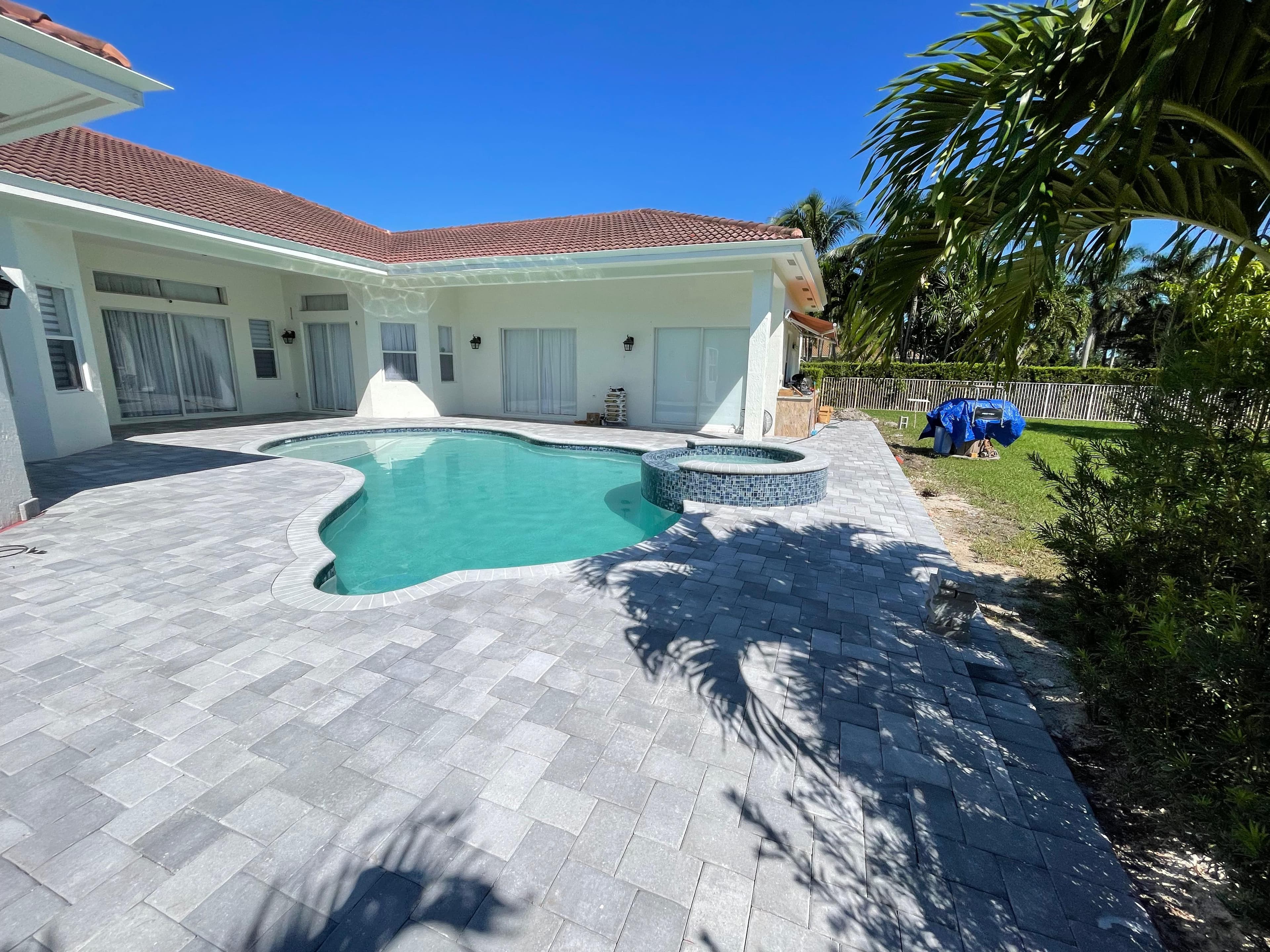 Pool and spa with blue mosaic tile accents and gray paver decking